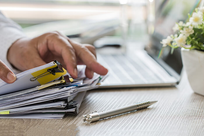 businessman-hands-holding-pen-working-stacks-paper-files-searching-information-business-report
