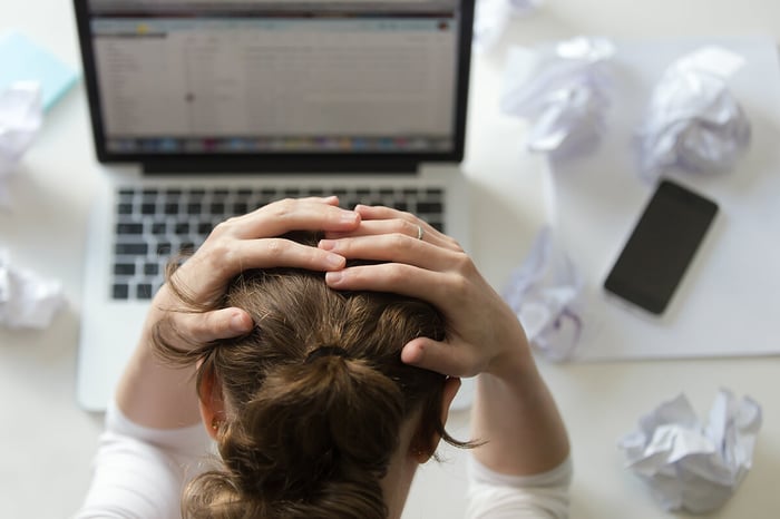portrait-woman-grabbing-head-desk-near-laptop